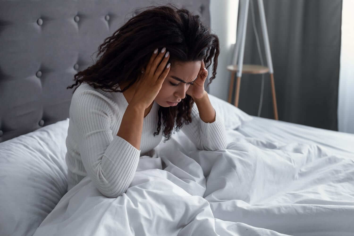 Vrouw ligt in haar bed en heeft last van hoofdpijn.