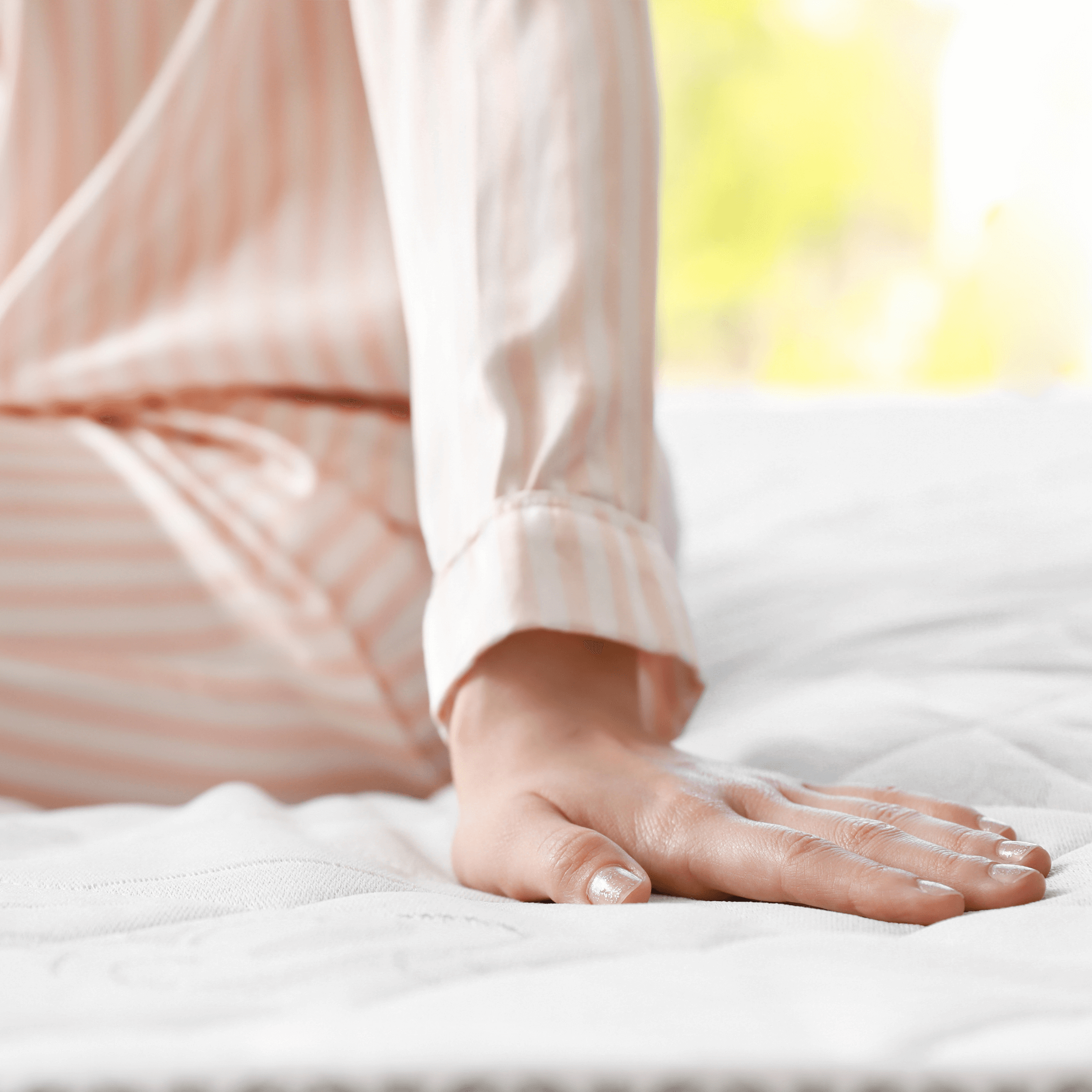 Vrouw in pyama die haar hand legt op een matras.